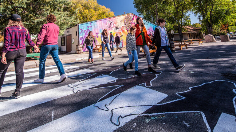 people at a cross walk in front of the brewery arts center