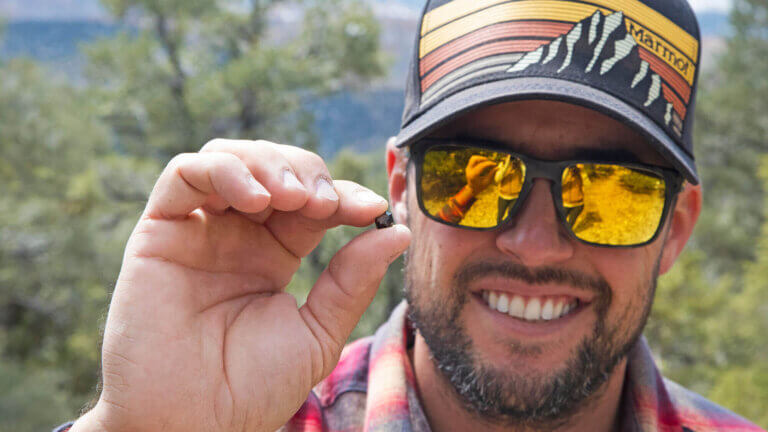 man shows off a pebble at garnet hill