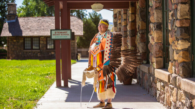 native american standing out front of the stewart indian school