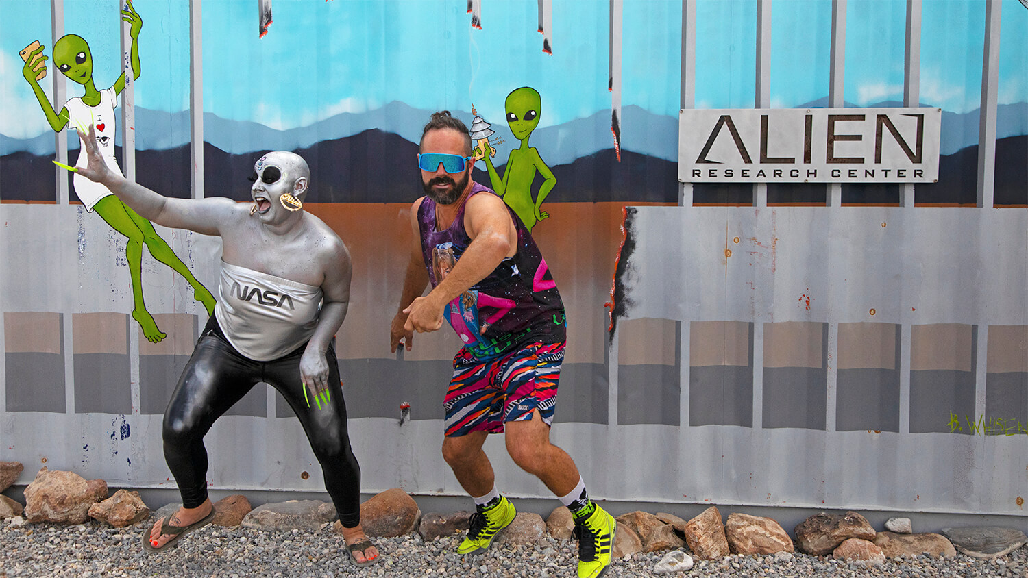 two people in costume stand in front of the alien research center at area 51