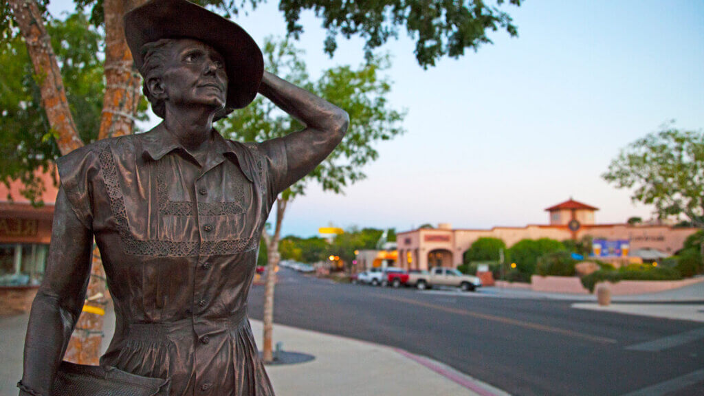 statue of a woman holding her hat