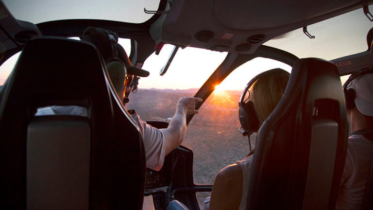 passengers looking out helicopter window at grand canyon sunset