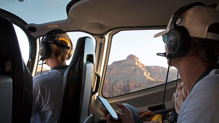 passengers looking out helicopter window at grand canyon