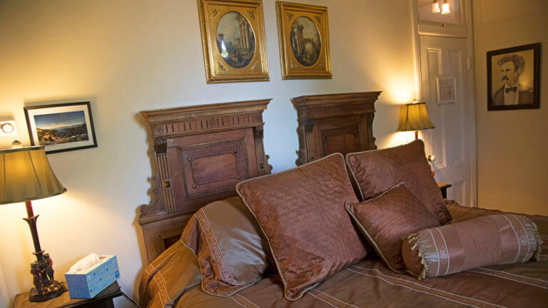 brown bed spread with wood base board at the cobb mansion bed and breakfast