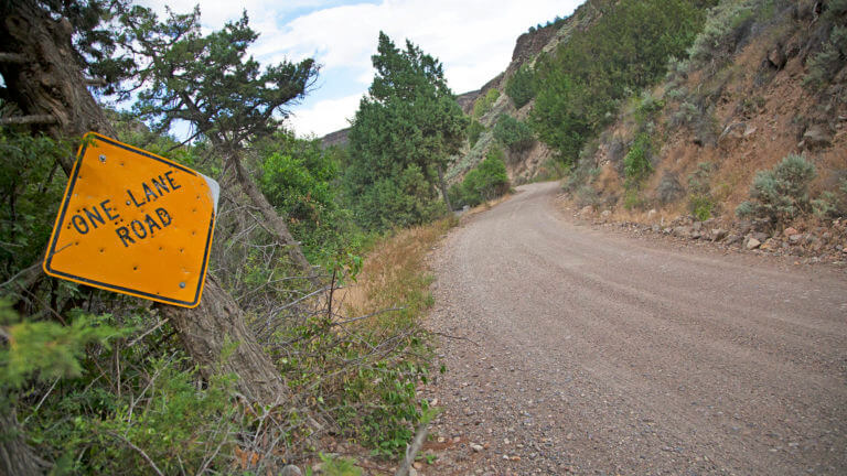 one lane road sign on dirt road