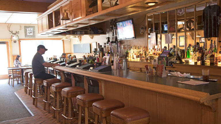 man sitting down on a stool at a bar