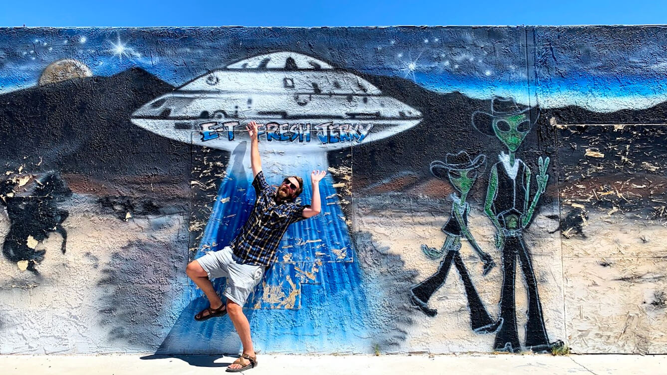 Man posing in front of alien mural