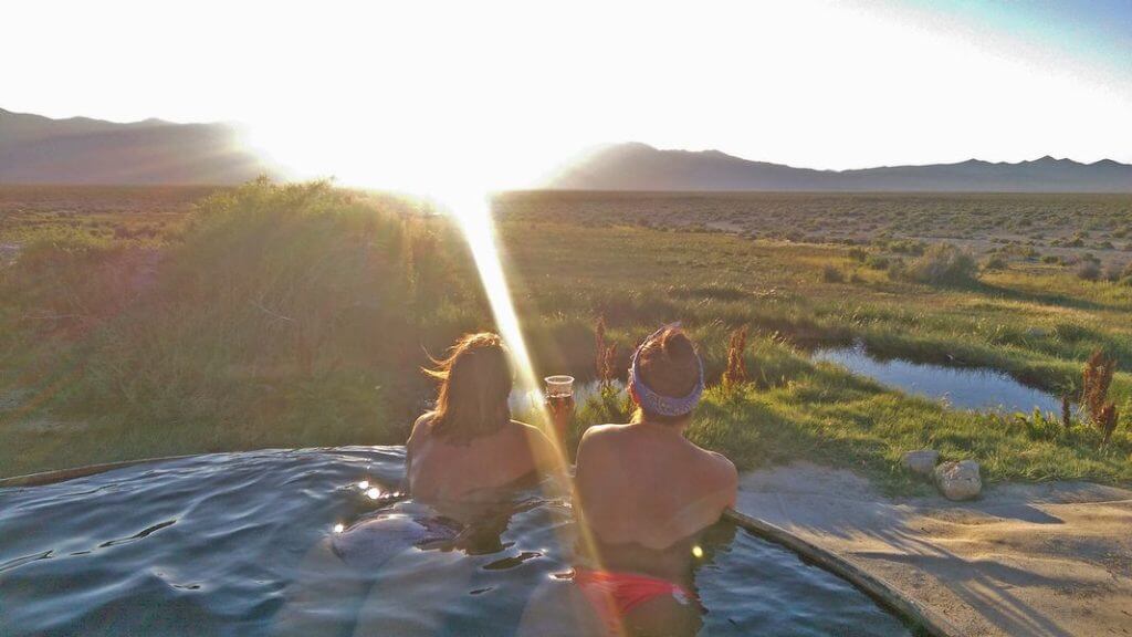 two people enjoying the sunset in a hot spring