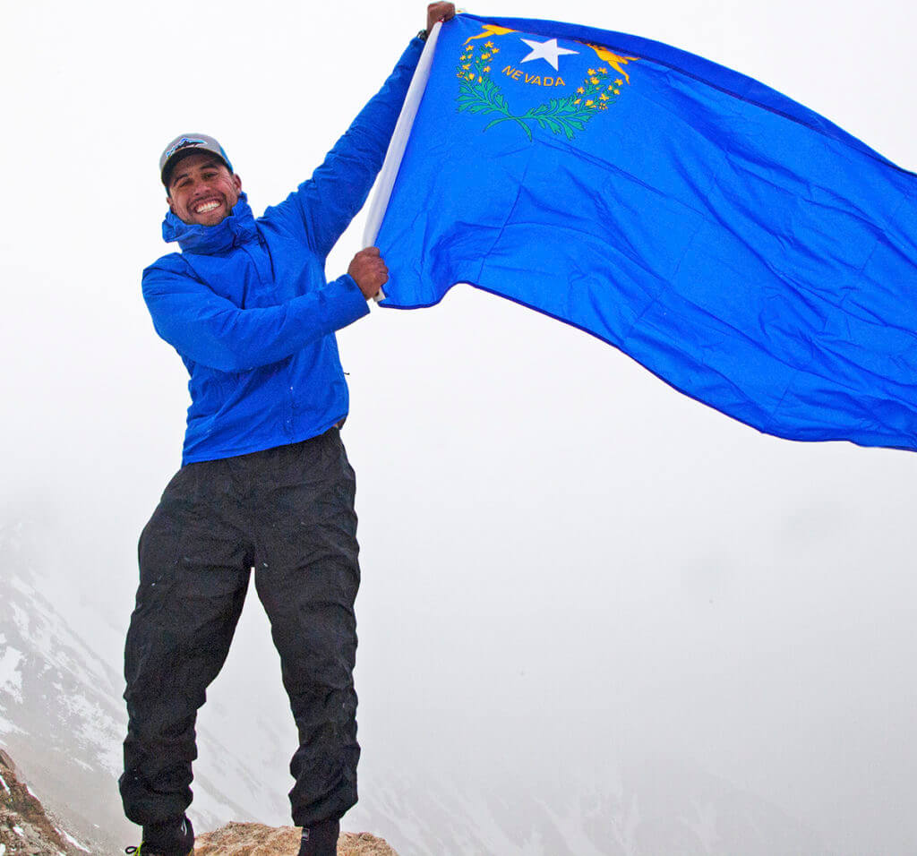man waving a nevada state flag at boundary peak