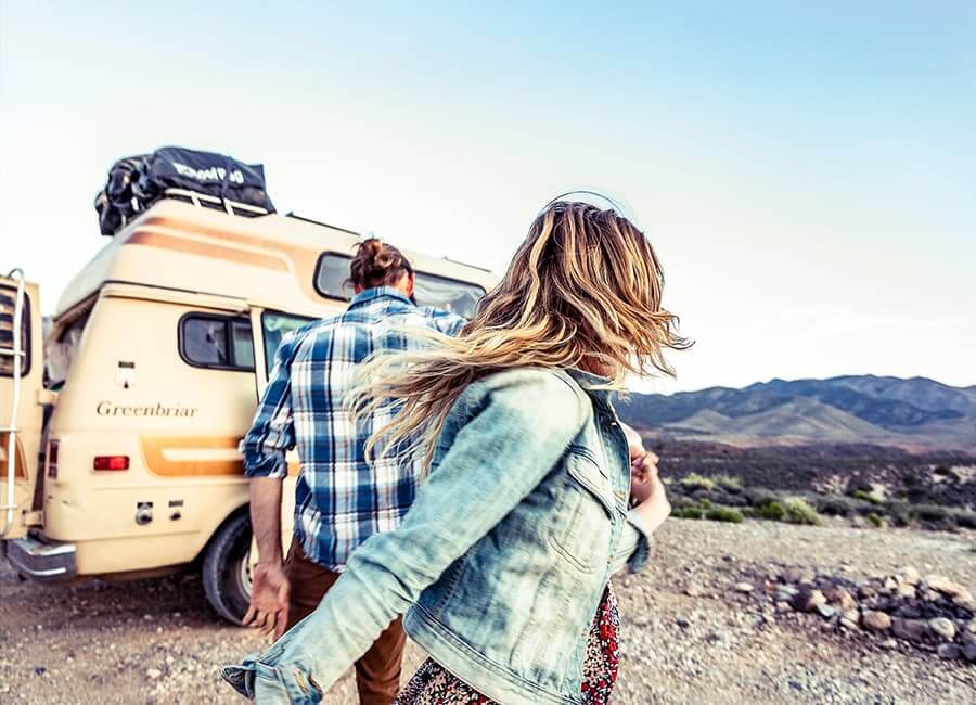 Two people near a van in front of mountains