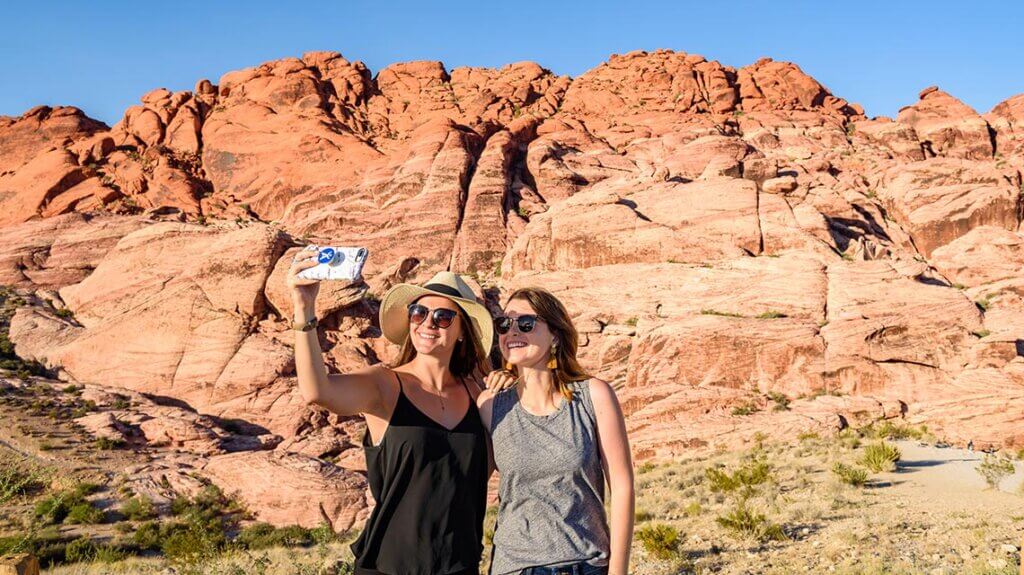 two women taking a selfie in front of a rock wall in the valley of fire