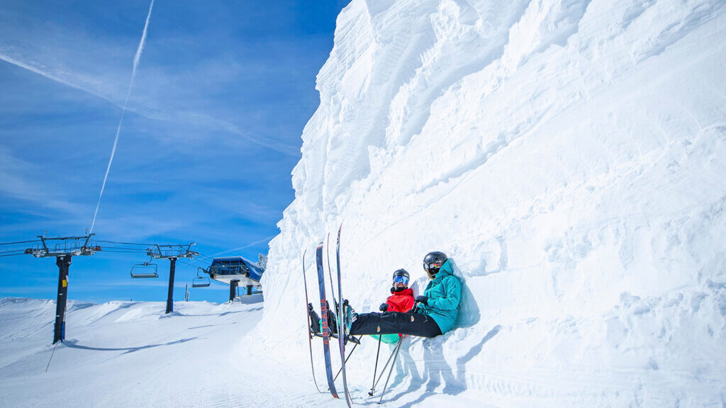 two skiers sitting down on snow near palisades tahoe lodging