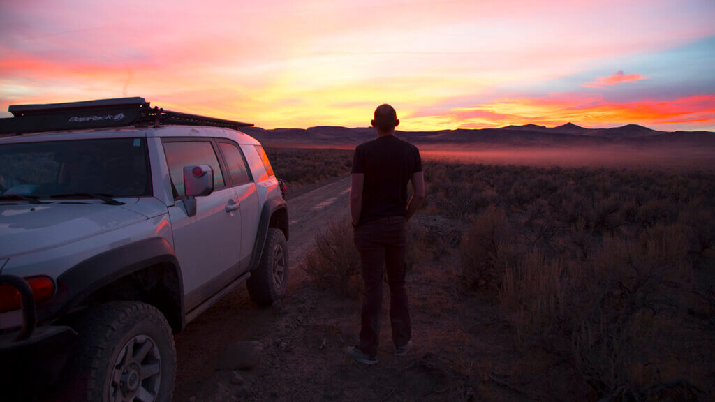 man watching sunset next to his fj cruiser in high rock canyon