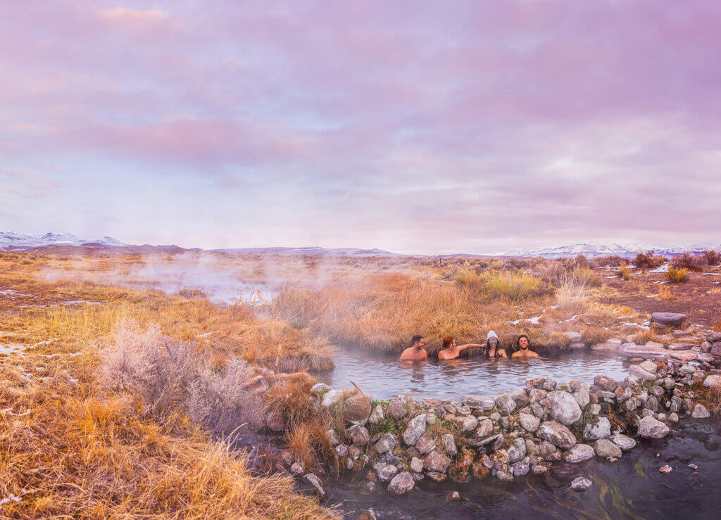 four people soak in a hot spring at burner byway