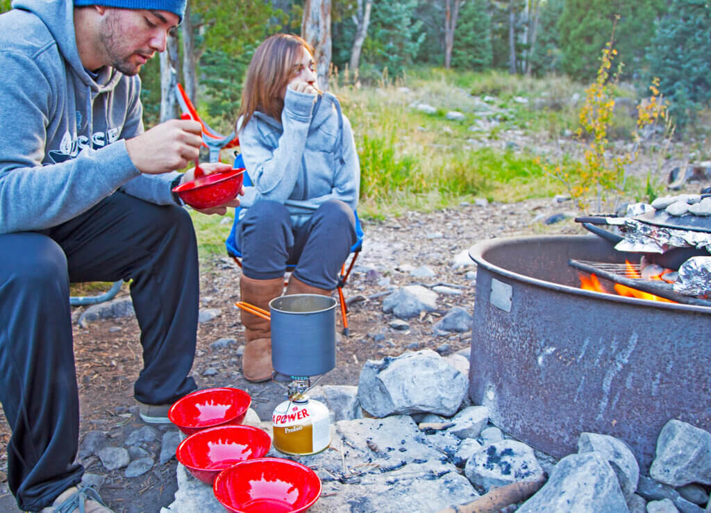 two people cooking food fire side in great basin national park
