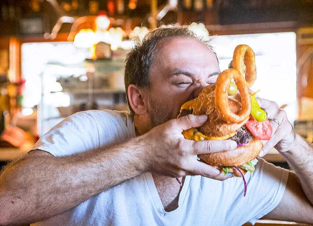 man taking a giant bite out of the middlegate monster burger challenge