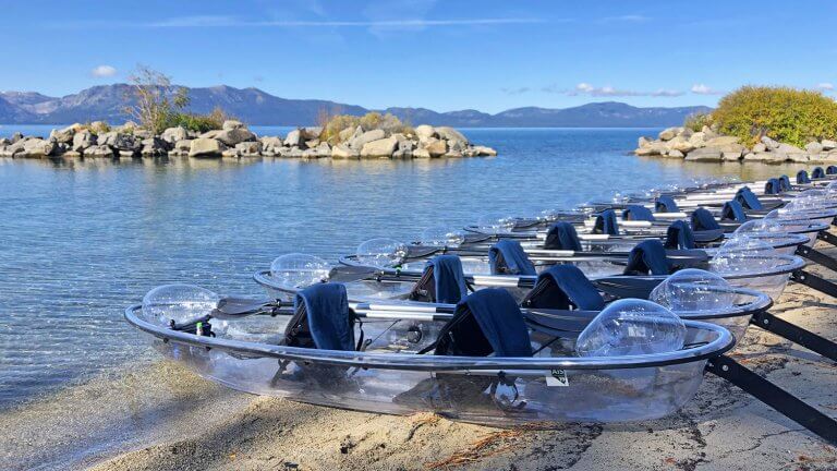 clear kayaks lined up on tahoe shore