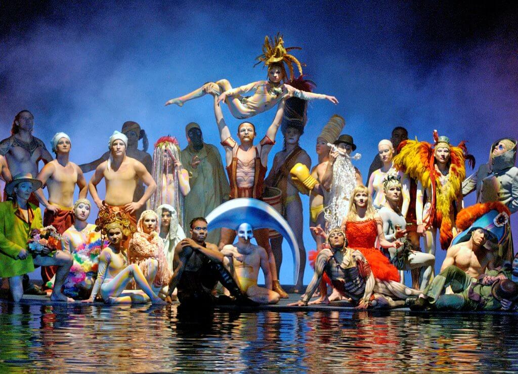 cast of cirque du soleil in front of water