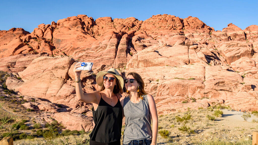 two women taking a selfie in front of mountains