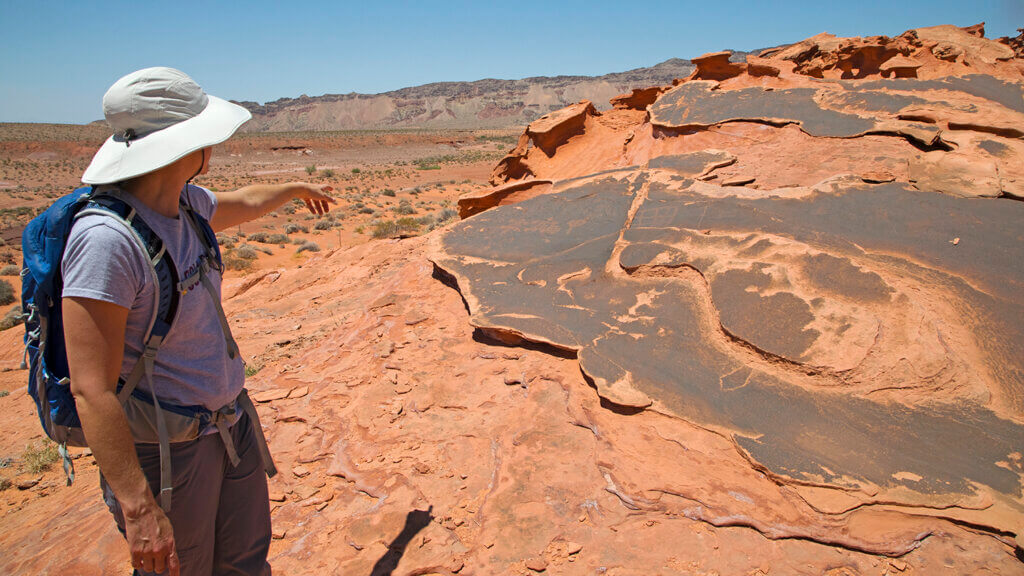 visitor inspects red rocks in gold butte