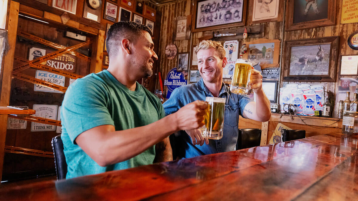 two men with beers inside happy burro in beatty nevada
