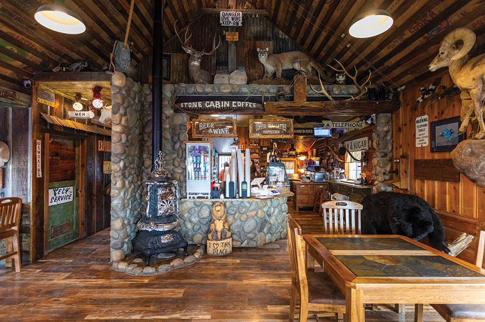 The interior of Stone Cabin Coffee, with a potbelly stove, lots of stone work, wood, and stuffed/mounted wildlife.