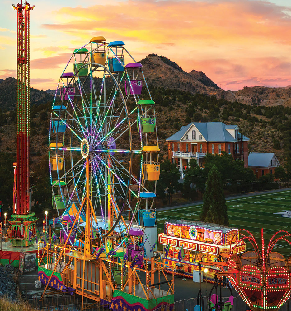 A colorful carnival scene, with a ferris wheel, and St. Mary's Art Center in the background.