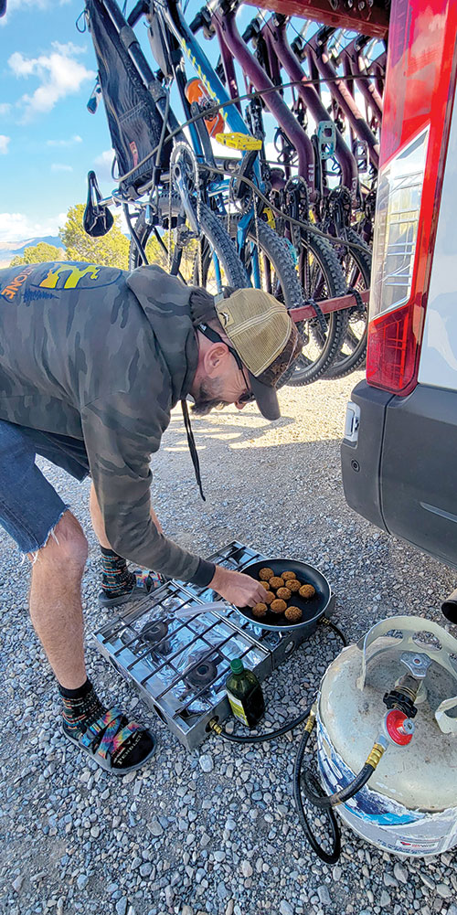 Ward Charcoal Ovens State Park - A man cooks falafel on a camp stove, with mountain bikes hanging behind him, off the back of a van.