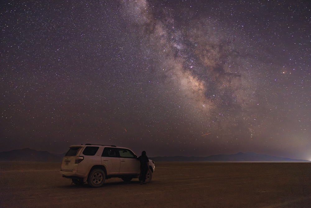 Woman standing next to a car underneath the Milky Way on the Black Rock Desert.