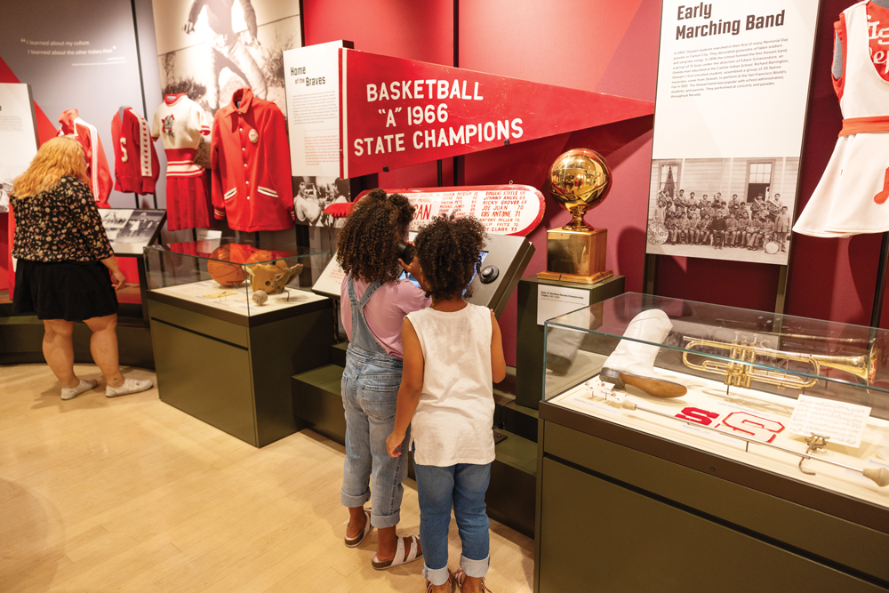 Mom with two children reading about Stewart Indian School in their museum. 