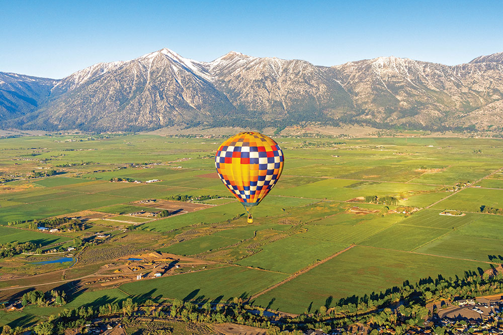 A hot air ballon (shot from above) with the Carson Valley and Sierra Nevada mountain range (Jobs Peak) in the background