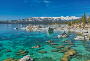 Two people kayaking along the shore of Lake Tahoe.