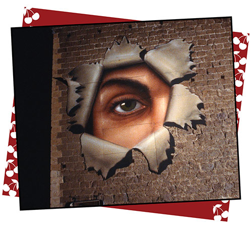 A mural of a giant eye, peeking through a hole, on the brick John S. Cook Bank building. ©provided by Gail Adler - courtesy of Annie and Sam Pressman and the Pressman Archives at The Academy of Motion Pictures Library