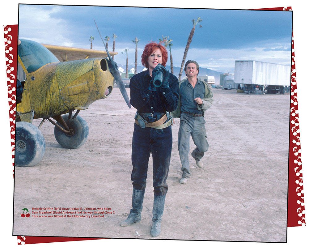 Melanie Griffith and David Andrews, on set for Cherry 2000. There is a yellow plane to the left of them, and tractor trailer and campers to the right and behind. ©provided by Gail Adler - courtesy of Annie and Sam Pressman and the Pressman Archives at The Academy of Motion Pictures Library