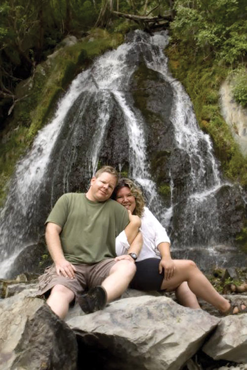 A couple sits in front of a waterfall. ©Christi Tolbert