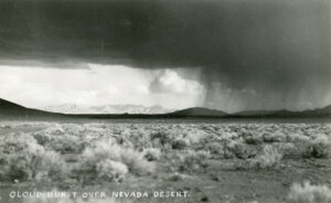 Desert landscape with a cloudburst in the distance.