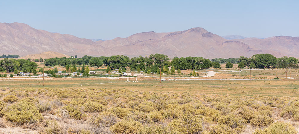 A panoramic view of Walker River State Recreation Area. Buildints, trees, and paved walkways.