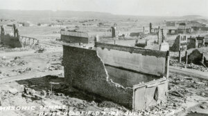 Overview shot of ruined buildings dotting the streets. Brick columns and walls remain after the fire.