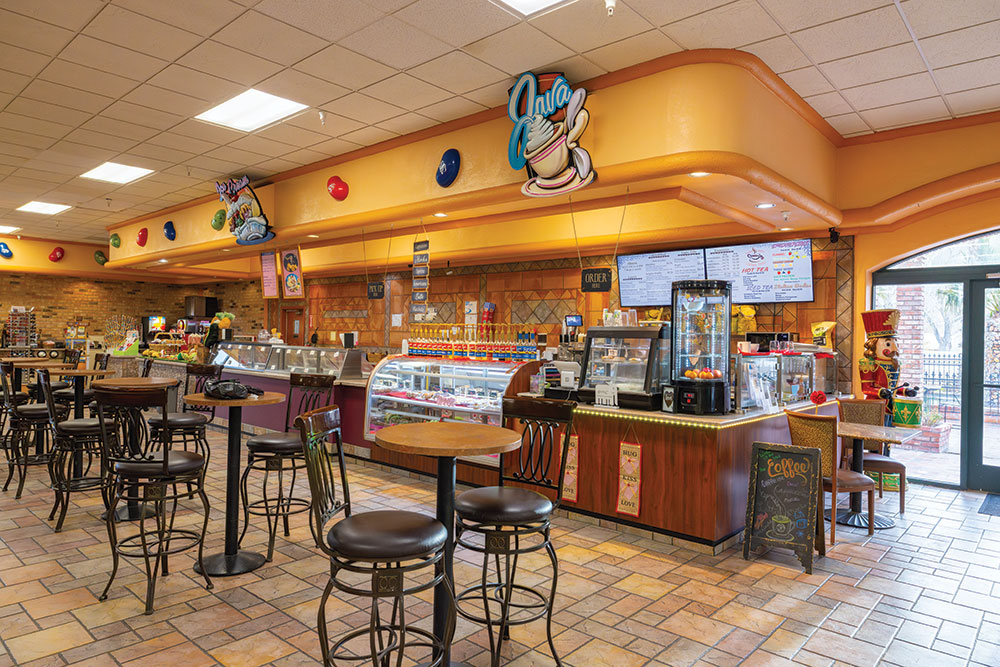 A colorful coffee counter with pastries and tables to sit at