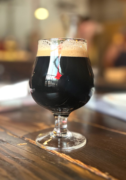 A glass of dark beer on a distressed bartop, at Great Basin Brewing Company.