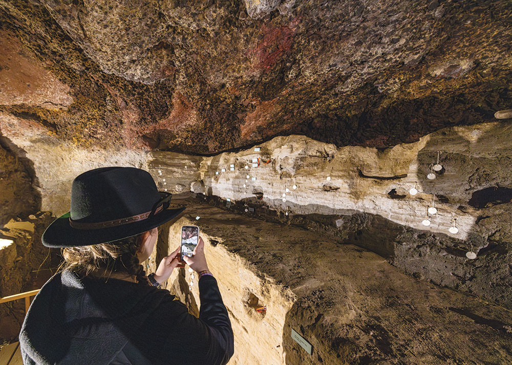 A young woman takes cell photos of cave markers inside Hidden Cave.
