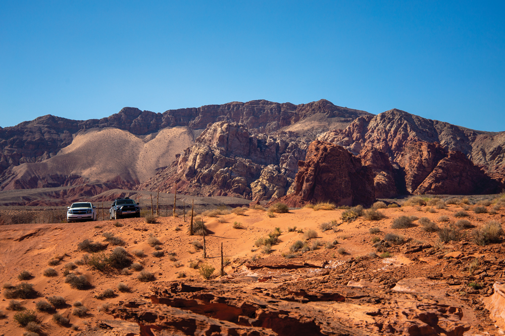 Two cars sitting in front of a mountain at Little Finland in Gold Butte.