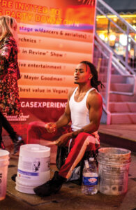 Jared Crawford sitting at Fremont Street Experience playing drums on buckets.