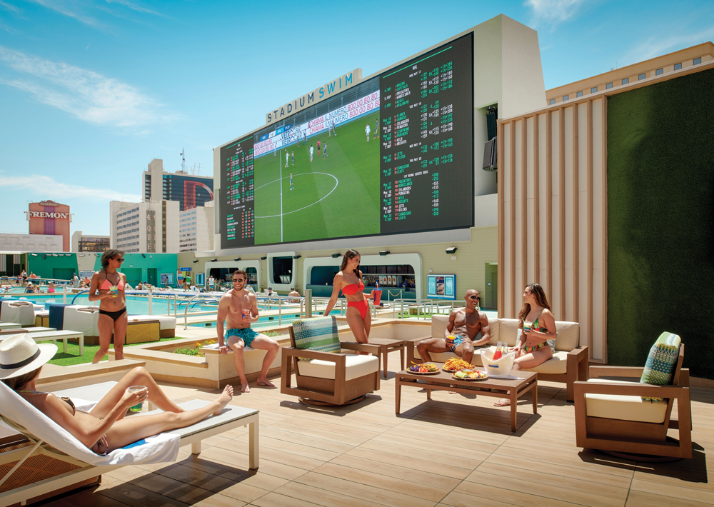 Group of people sitting on deck by a pool at Stadium Swim. 