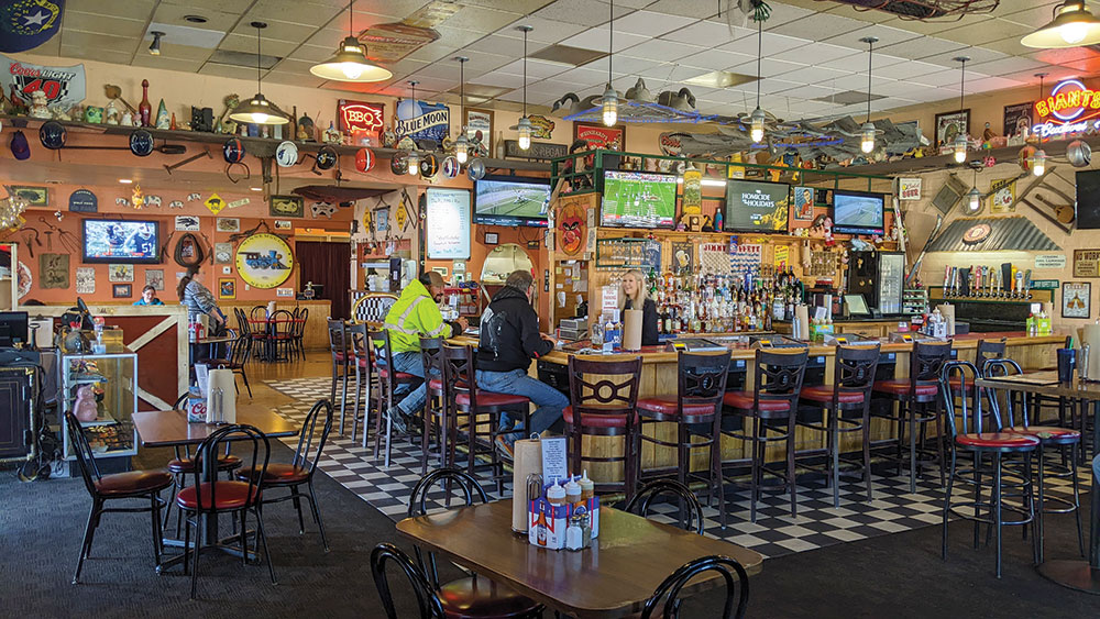 A bartender and two patrons chat at the bar inside The Pig.