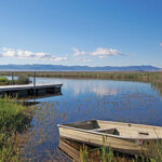 A wooden rowboat sitting in the water, next to a dock