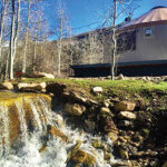 A tan yurt sits alongside a river high in the Ruby mountains