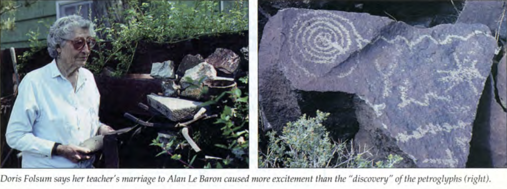 Elderly person by rocks: Person stands by rocks, artifacts; stone displays spiral petroglyphs. Caption: Debra Feldman.