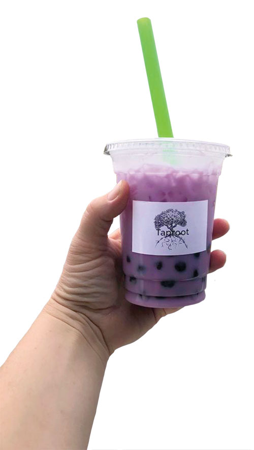 A lavender-colored iced drink is held in someone's hand