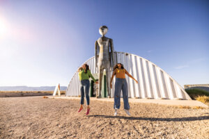 Two women jumping outside the Alien Research Center.